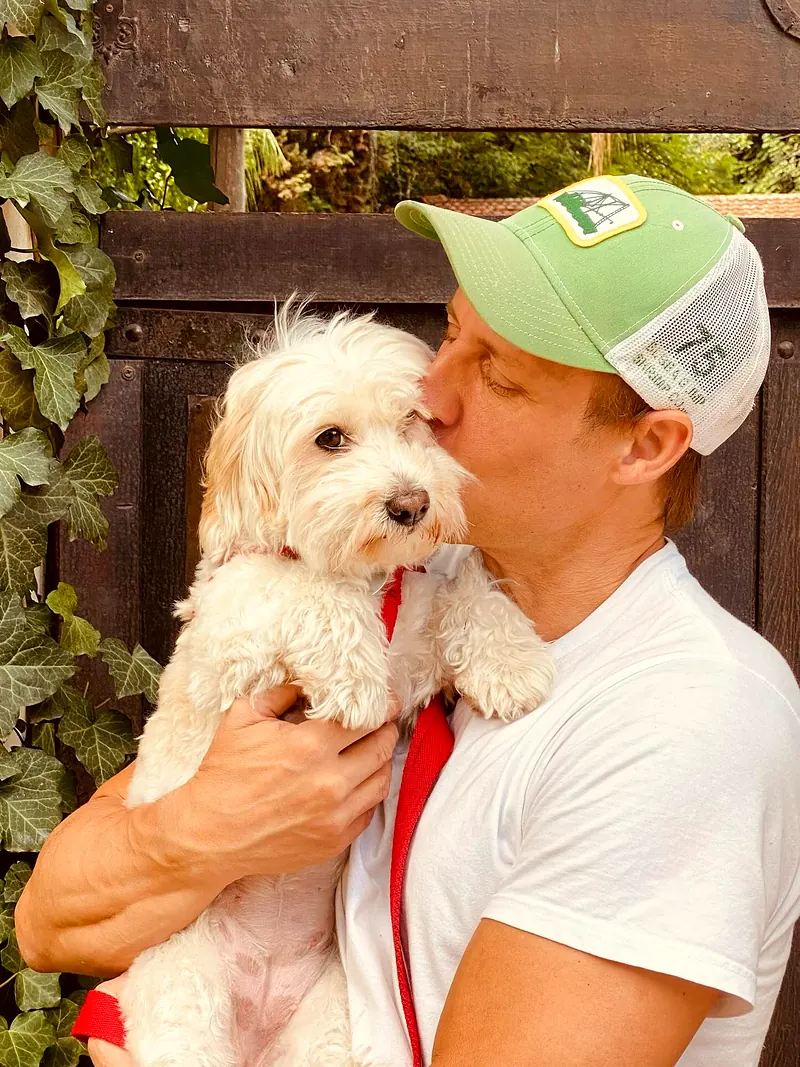 Marcelo dándole un beso a un caniche blanco