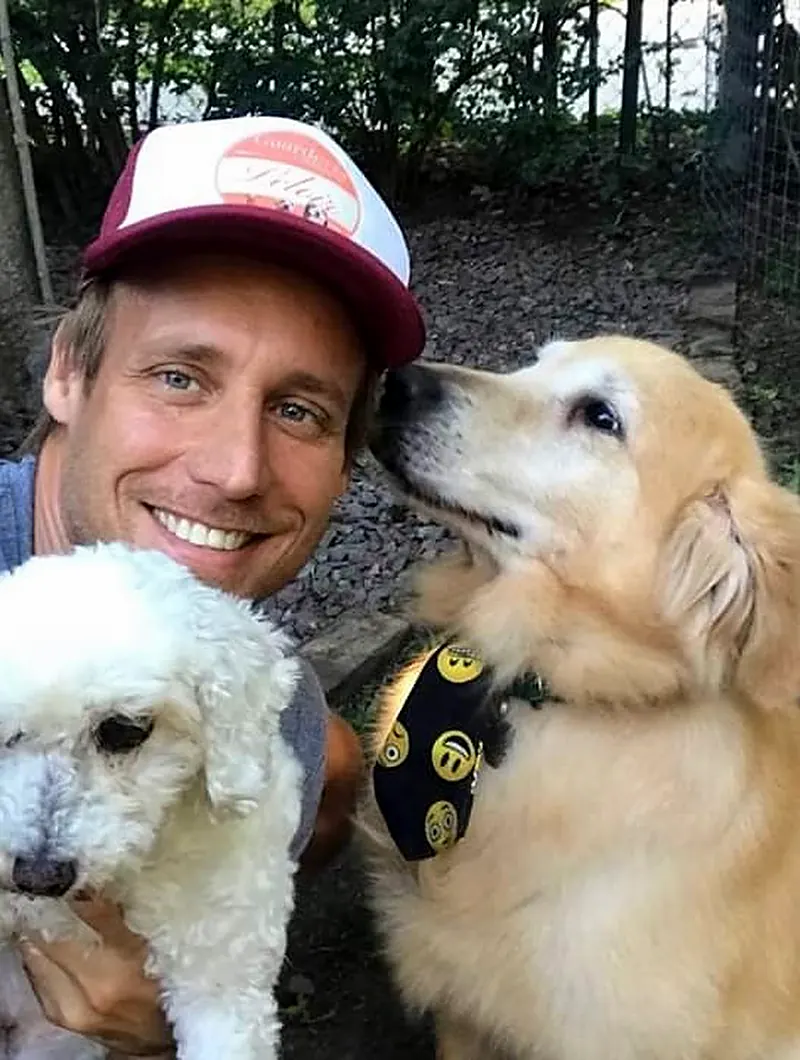 Marcelo sonriendo junto a un golden y un perro blanco