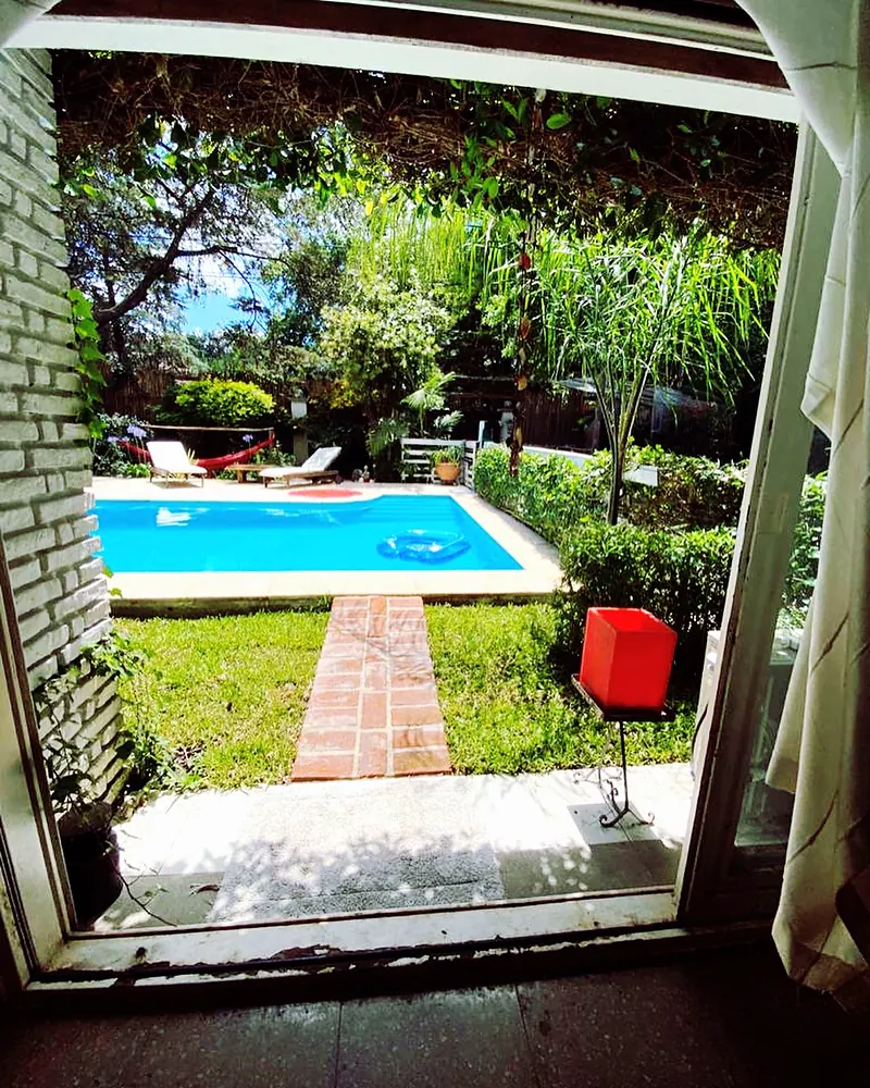 La pileta y el jardín vistos a través de la puerta abierta de la casa